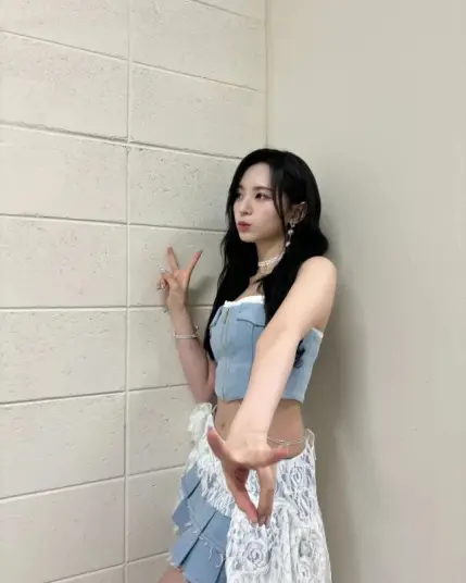 Kpop idol Mashiro thrusting one arm towards the camera with fingers inan unusual position.