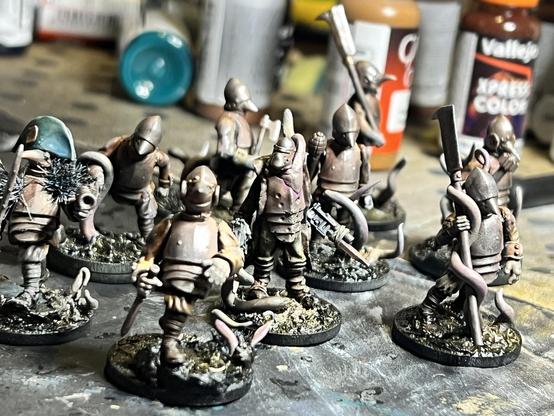 A bunch of figures in rusty armour, slogging through mud and tangled in choking roots