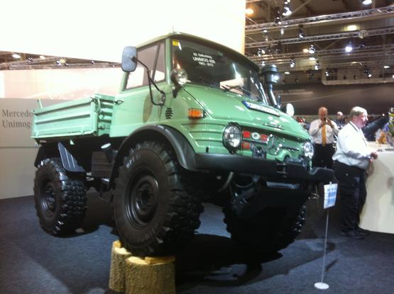 Green Mercedes Unimog 406 with one front wheel up on logs, front quarter view