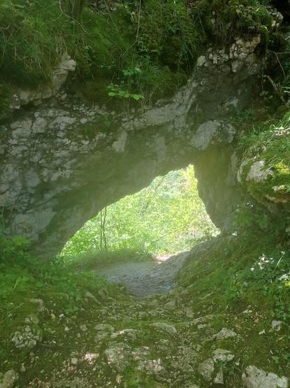 Au bas d'une crête rocheuse, s'ouvre une petite arche sous laquelle passe un sentier informel.