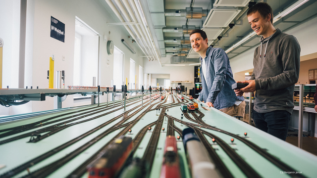 Fotoaufnahme von zwei jungen Männern im Eisenbahnbetriebslabor der TU Dresden.