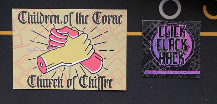 Two stickers. The sticker on the left shows a children of corne and church of Chiffre unity sticker with a handshake and the right one shows the CCH logo