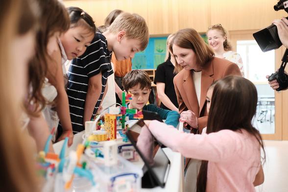 Staatssekretärin Sandra Boser mit Grundschülerinnen und Grundschülern an einem Tisch mit Robotik-Sets. Foto: Michael Damböck