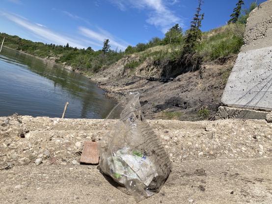 A small bag of garbage collected in the foreground. A very clean riverbank in the background!