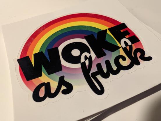 Sticker with rainbow on the background and the text "WOKE as fuck" over it.