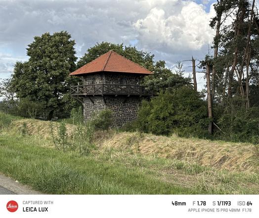 Der Limesturm bei Watzenborn-Steinberg, Gemeinde Pohlheim, Landkreis Gießen. Der Turm steht hinter einem kleinen Erdwall und ist von einigen Bäumen an drei Seiten umgeben. Leicht dramatische Wolken.