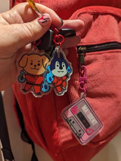 Keys with keychains of Wolf Chan & PuppyM in their Thunderous outfits, and a Maxident cassette keychain on a pink corduroy backpack