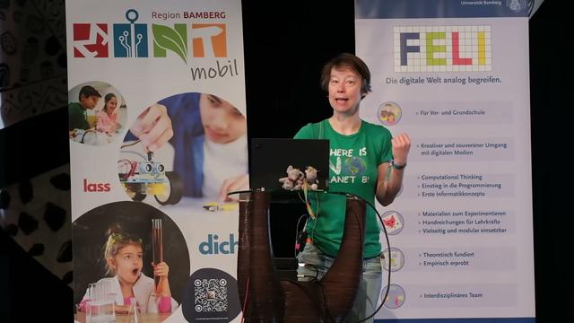 Sanne Grabisch am Rednypult – im Hintergrund zwei RollUps, links MINTmobil: „Lass dich begeistern“ rechts FELI: „Die digitale Welt analog begreifen“ – bei ihren Kurzvorträgen auf dem IGERla am 8.6.2024