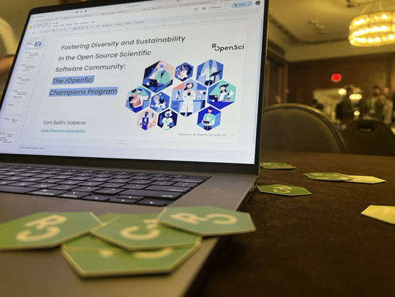 rOpenSci stickers and a laptop with slides about the champions program.