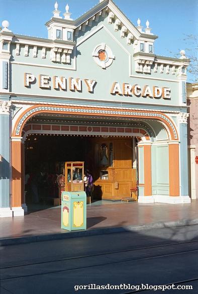 Entrance to a vintage-style Penny Arcade with a pastel-colored facade and a trash can in front.