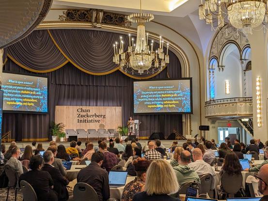 A woman on a stage in front of an audience. Behind her is a sign that reads Chan Zuckerberg Initiative and two screens that read "What is open science?

The principle and practice of making research products and processes available to all, while respecting diverse cultures, maintaining security and privacy, and fostering collaborations, reproducibility, and equity."