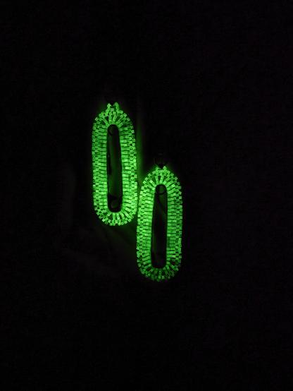The same pair of earrings but in the dark showing how bright the beads illuminate. Not a pale green anymore!