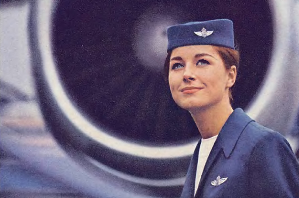 1968 Flying Aviator in Uniform

The image shows a woman dressed in a navy flight suit, standing in front of an airplane.
She appears to be looking to the side with a slight smile, and her gaze seems directed towards something off-camera.
The woman's posture suggests confidence, and she is wearing the standard uniform for aviators in the U.S.
Navy.