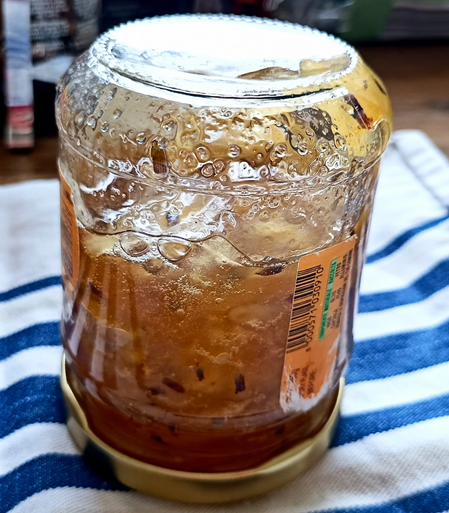 Ein Glas mit eingefüllter Marmelade auf dem Kopf stehend auf einem Geschirrtuch
