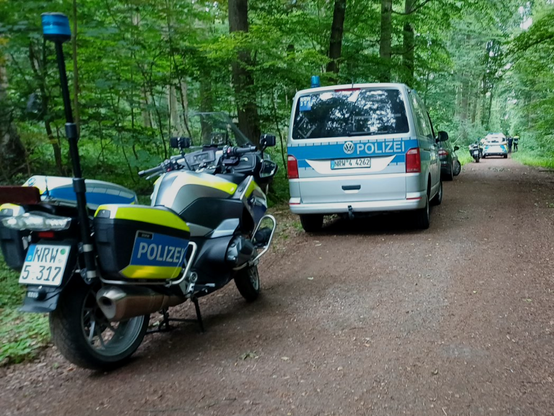 Polizeimotorräder und Transporter stehen auf dem Waldweg bei der Besetzung #GrembiBleibt