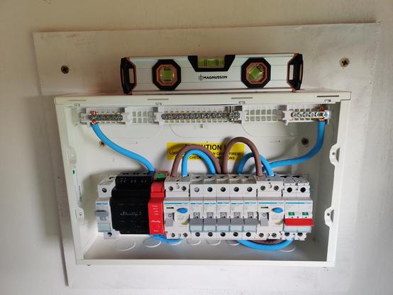 close up view of the consumer unit which has two Shelly smart relays fitted. a spirit level sits on top. yes. it is level.