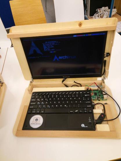 Modulares Notebook mit handgesägtem Holzgehäuse. Auf dem Display ist eine Arch-Linux-Konsole zu sehen.
