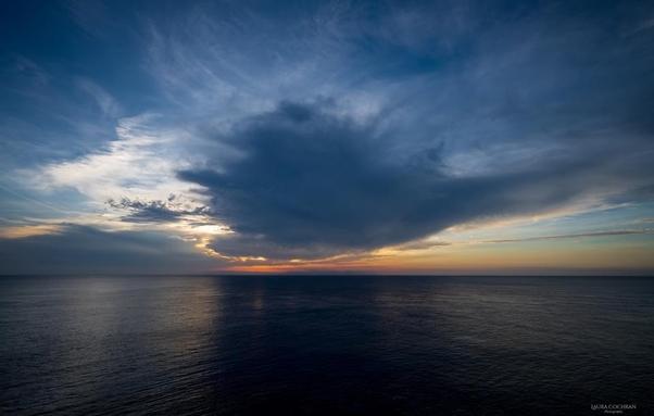 A large cloud over the sea at sunset.