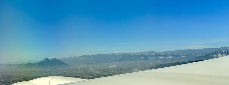 Aerial view of Monterrey’s mountainous landscape with a clear sky, taken from an airplane window.