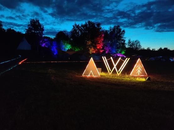 VVOIDcamp logo made out of wood with LED edge lighting.
RGB spots on threes in the background.