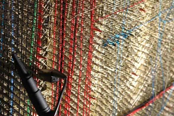 An oscilloscope probe connected to pins on a wirewrapped backplane.