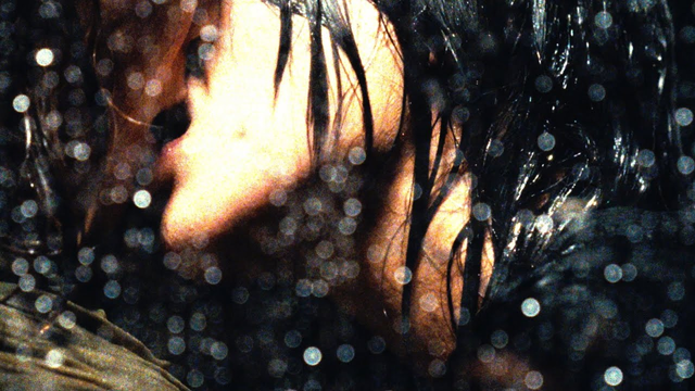 A close up of of SoYoON kissing a girl in the rain
