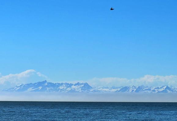 There was some heavy fog at the base of the mountain range in Cook Inlet, but also, a helicopter flying overhead. Photo take from the beach.