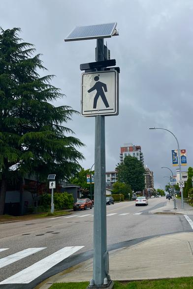 una señal de un cruce peatonal con iluminación con celdas solares