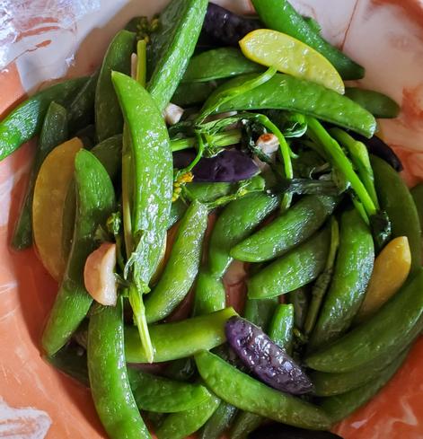 Fried geen, yellow & purple snow peas with garlic. In marbelized peach & white coloured bowl.