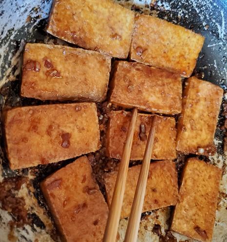 Fried soy, garlic, lemongrass tofu - in wok, with chopsticks.