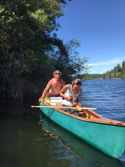 In a green canoe, with a friend - who is doing yoga stretch behind me. On a lake. Sunny day.