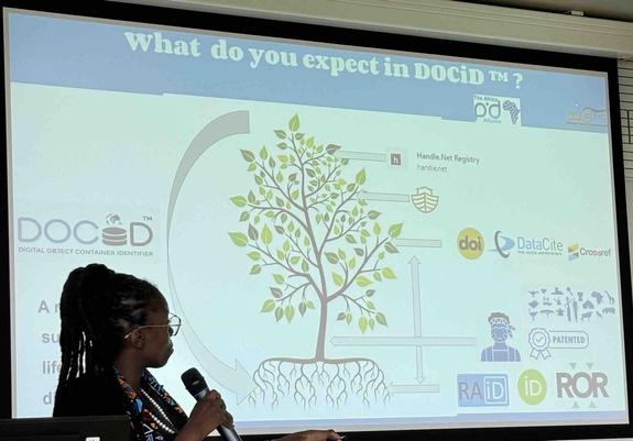 Screenshot of presentation slide where a Digital Object Container Identifier (DOCiD) is depicted as the trunk of a tree and where other persistent identifiers (archival resource keys (ARKs), Handles, etc.) serve as a root system, branches, leaves, etc.