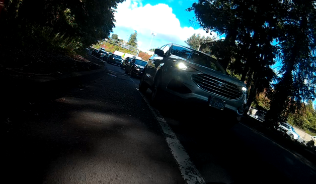 ford SUV with oregon plate CA 25436, stopped on the bike lane stripe on a curve