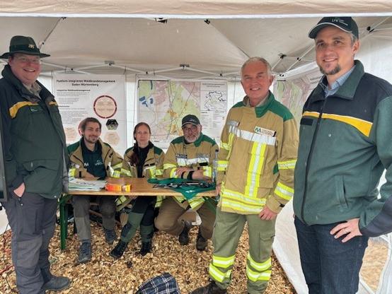 Forstexpertinnen und Forstexperten auf einem Informationsstand zum Thema Waldbrand.