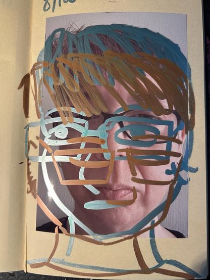 A photo of a white woman’s face. She has short brown hair and rectangular glasses with dark frames. The photo is pasted into a sketchbook and over it are drawn two cartoon versions of her face, one a bit down and to the left done in green metallic paint pen, the other further down and to the right in a kind of reddish metallic paint pen.