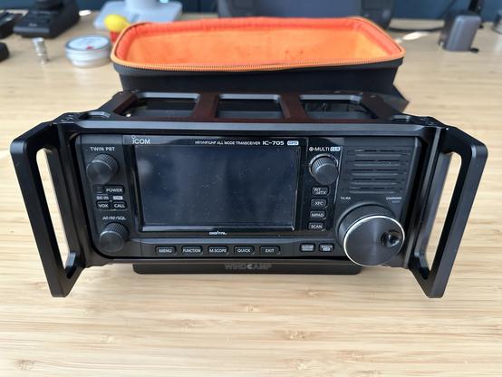 An Icom IC-705 in an ARK cage sitting on a desk.