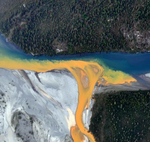 photo - aerial view of the Kutuk River in Alaska's Gates of the Arctic National Park that looks like orange paint spilling into the clear blue water.