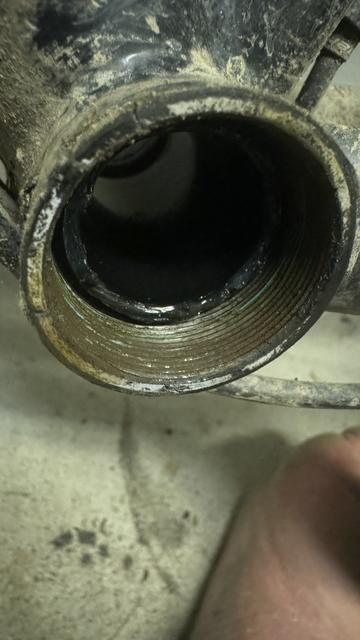 Nahaufnahme einer schmutzigen, eingefädelten kreisförmigen Öffnung an einem mechanischen Teils eines Fahrradrahmens.