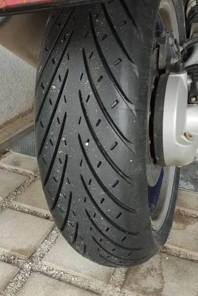 Hinterreifen eines Motorrads. Das Motorrad steht auf Pflaster.
