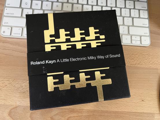 A photo of the outer box with beautiful gold foil stamp of abstract art by Robert Beatty, which when looking closer at the artwork for each disc, it seems like a microcosm of a ridiculously intricate illustration to represent this very large suite of music.