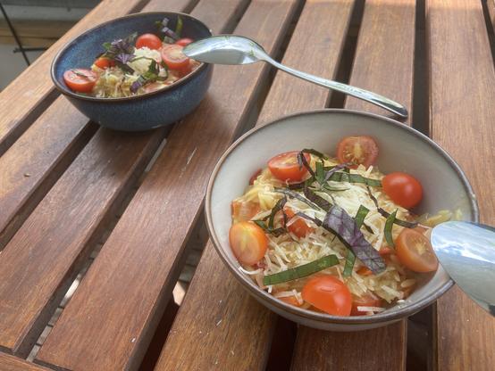 Zwei Schalen Orzo mit Tomaten, Parmesan und Basilikum