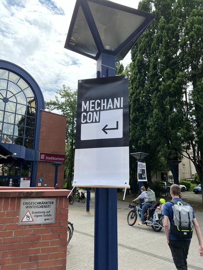 Eingang zum SAALBAU. Ein großes Mechanicon-Banner hängt an einer Laterne.