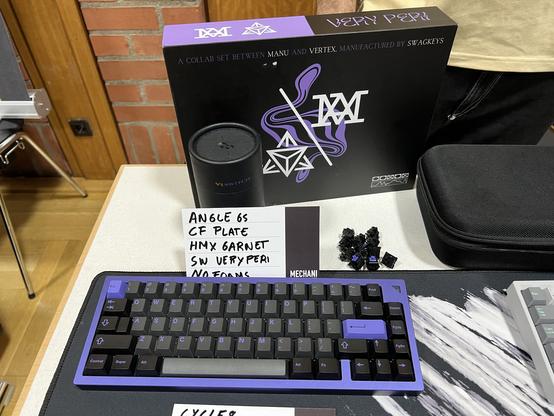 Eine Angle 65-Tastatur aus Aluminium in lilafarben Gehäuse. Die Keycaps sind schwarz-lila.
