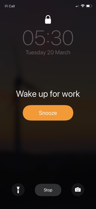 An iPhone screen showing the time as 05:30 with an alarm notification named "Wake up for work" and a "snooze" button.