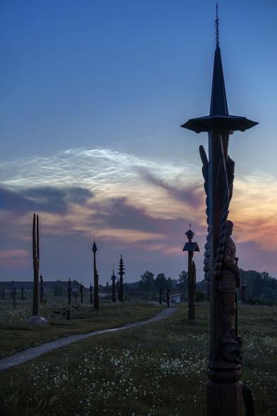 Sunrise at The Hill of Angels near Vilnius with angel sculptures in the foreground and silver clouds in the background