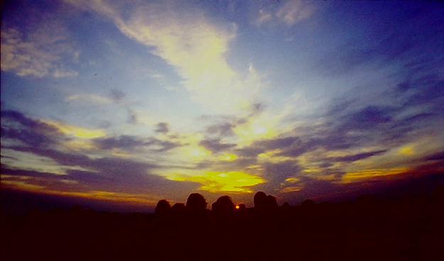 A colourful sunrise, viewed across a ring of standing stones