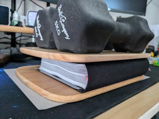 The book sitting in a press made from two boards and some weights on top.