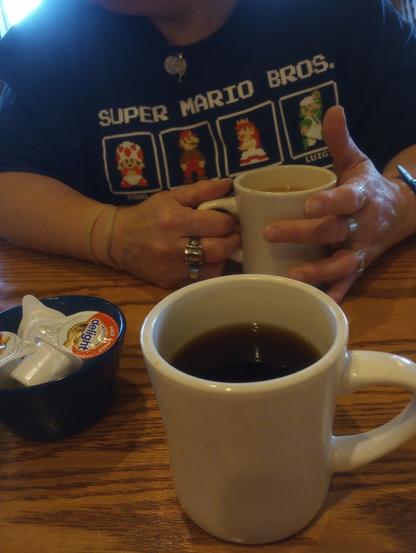 At Cracker Barrel with coffee in hand with D. in a Mario Character T-shirt.