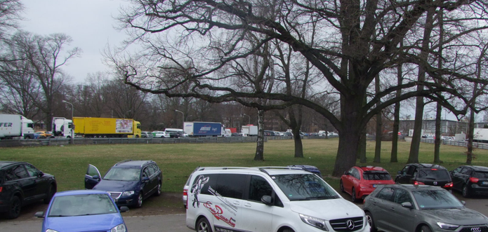 Autos parken in einer Grünfläche, auf der Wiese neben einem Weg