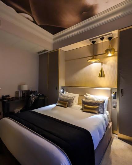 A very comfy queen size bed in the middle of a gold accented room (pillows, lamps, wardrobe frames etc.). I'm usually not a fan of gold but this is done tastefully.